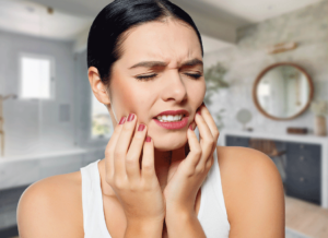 A woman clutching her jaw in pain from a dental emergency.