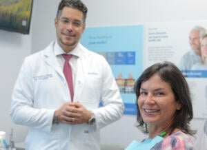 A dentist and patient smiling in an exam room.